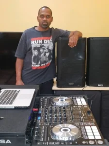 man with arm over speakers in front of a turntable