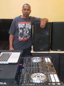 large image of man with arm over speakers in front of a turntable
