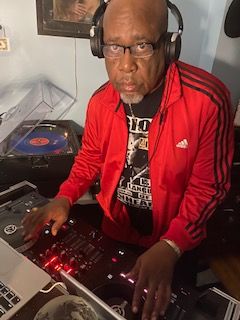 DJ wearing red jacket and on a DJ turntable
